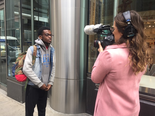 Woman holding camera filming student