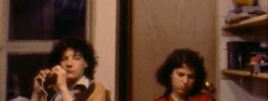 Still from the film showing a guy and girl sitting against a wall