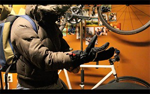 Still from the film showing a person putting on a glove while sitting on a bike